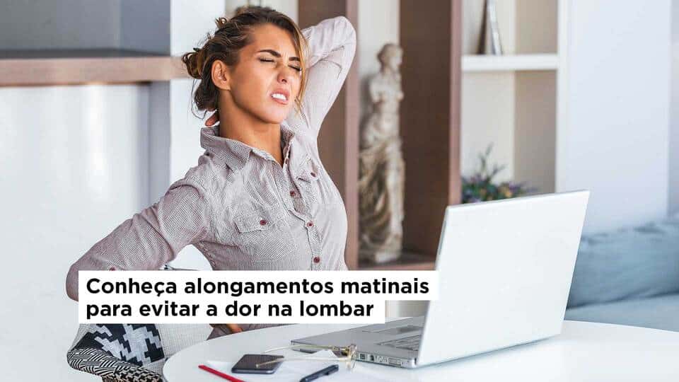 Mulher sentada na frente do notebook com a mão nas costas sentindo dor na lombar -alongamentos matinais para prevenção de dor na lombar de quem trabalha sentado