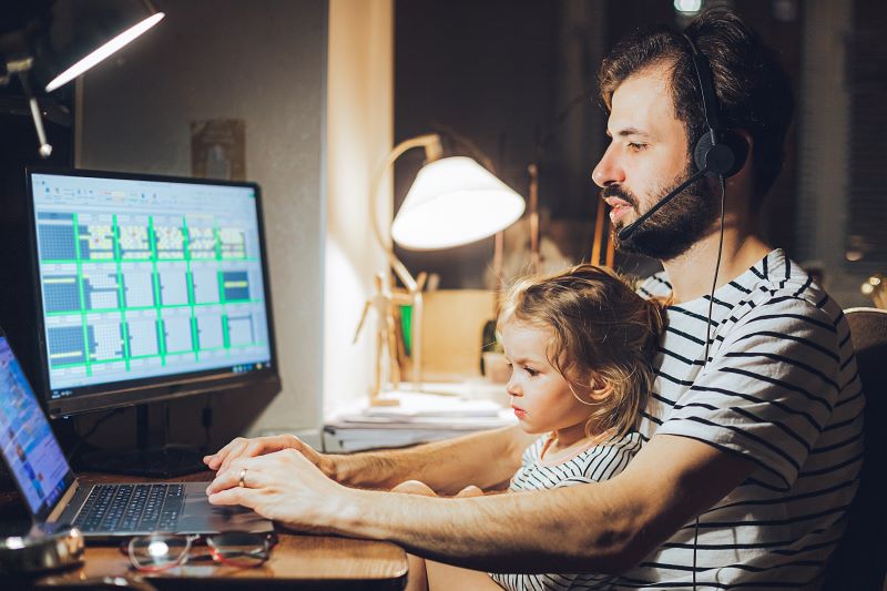 Homem trabalhando em casa com sua filha.
